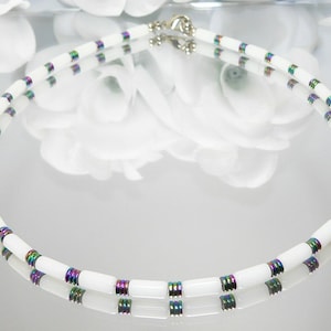 May include: A white and iridescent necklace with a silver clasp. The necklace is made of small, round beads with a white center and iridescent edges.