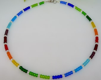 May include: A rainbow colored beaded necklace with silver beads interspersed throughout. The necklace is made of small, round beads and has a silver clasp.