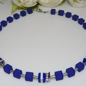 May include: A blue and white necklace with square beads and silver accents. The necklace is made of glass and metal.