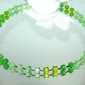 May include: A double strand necklace made of green glass beads. The beads are graduated in size and color, with the smallest and lightest beads at one end and the largest and darkest beads at the other end.
