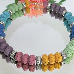 May include: A rainbow colored lava rock beaded necklace with silver spacers. The necklace is made of multiple strands of beads and has a clasp closure.
