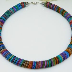 Könnte beinhalten: Eine bunte Halskette aus runden, flachen, mehrfarbigen Perlen. Die Perlen sind in einem sich wiederholenden Muster aus Blau, Grün, Braun, Lila und Orange angeordnet.