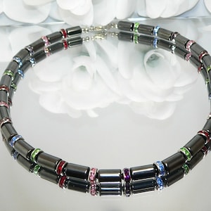 May include: A double-strand necklace made of black hematite beads with colorful crystal accents. The necklace features alternating beads of hematite and crystal, creating a vibrant and stylish look.