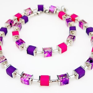 May include: A silver necklace with alternating pink and purple square beads. The beads have a clear, iridescent finish.