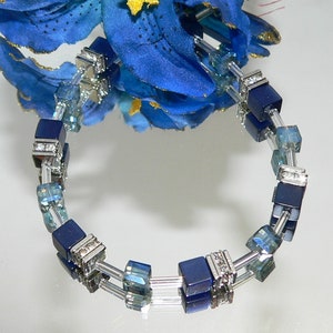 May include: A blue and silver bracelet with square beads and clear crystals.
