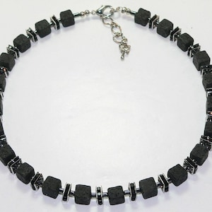 May include: A black lava rock necklace with silver accents and small black crystals. The necklace is made of square-shaped beads.