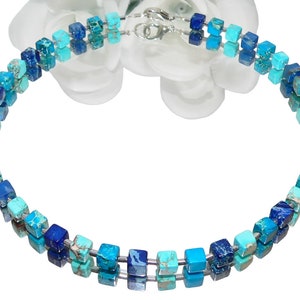 May include: A double-strand necklace made of blue and turquoise square beads. The necklace is made of natural stone and has a silver clasp.