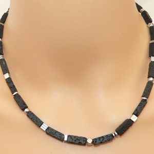 Peut inclure: Un collier en pierre de lave noire et perles argentées. Le collier est composé de perles rectangulaires et mesure environ 45 cm de long.
