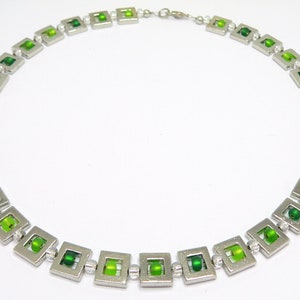May include: A silver necklace with green glass beads in square frames.