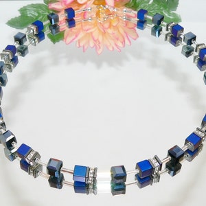 May include: A silver necklace with dark blue square-shaped beads and clear crystal accents.