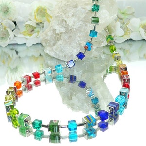 May include: A rainbow colored glass bead necklace with silver metal connectors. The beads are square shaped and have a variety of colors including red, orange, yellow, green, blue, and purple.