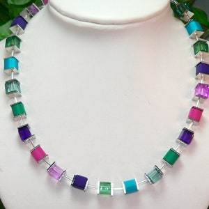 May include: A silver necklace with square-shaped beads in shades of turquoise, green, purple, and pink.