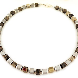 May include: A silver and gray stone necklace with square-shaped beads. The necklace is made of alternating silver and gray stones.