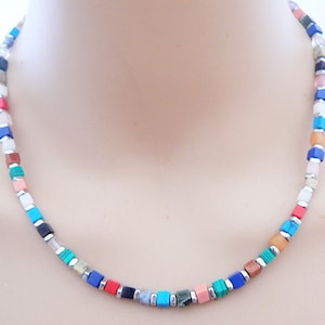 May include: A colorful necklace made of square-shaped gemstone beads. The beads are in shades of blue, green, red, orange, and white.