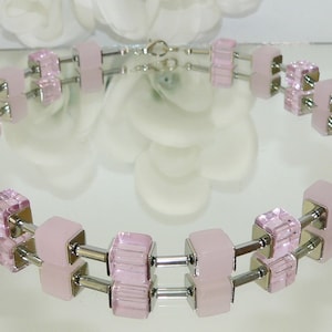 May include: A pink and silver necklace with square-shaped beads. The beads are made of glass and metal.