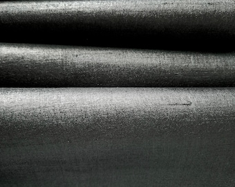 Könnte beinhalten: Nahaufnahme von schwarzem Stoff mit glatter, seidenartiger Textur. Der Stoff ist in einer Reihe von überlappenden Schichten gefaltet, wodurch ein welliger Effekt entsteht.