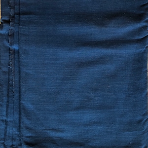 May include: A deep blue fabric with a smooth, slightly textured surface. The fabric is folded and has a raw edge.