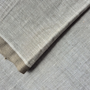 Może przedstawiać: Zbliżenie na szary materiał o subtelnej, tkanej fakturze. Materiał jest złożony na sobie, tworząc ukośną linię.