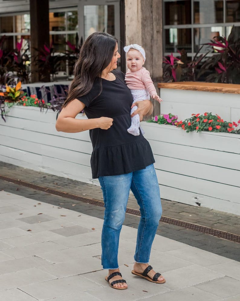 Mom holder her baby and opening the hidden nursing access on her breastfeeding tee.