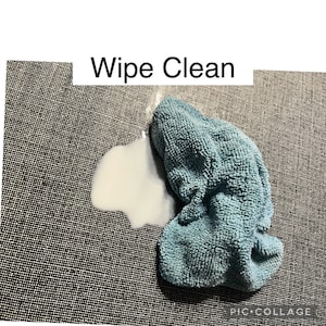 May include: A blue microfiber cleaning cloth on a gray textured surface with a white stain. The text "Wipe Clean" is above the cloth.