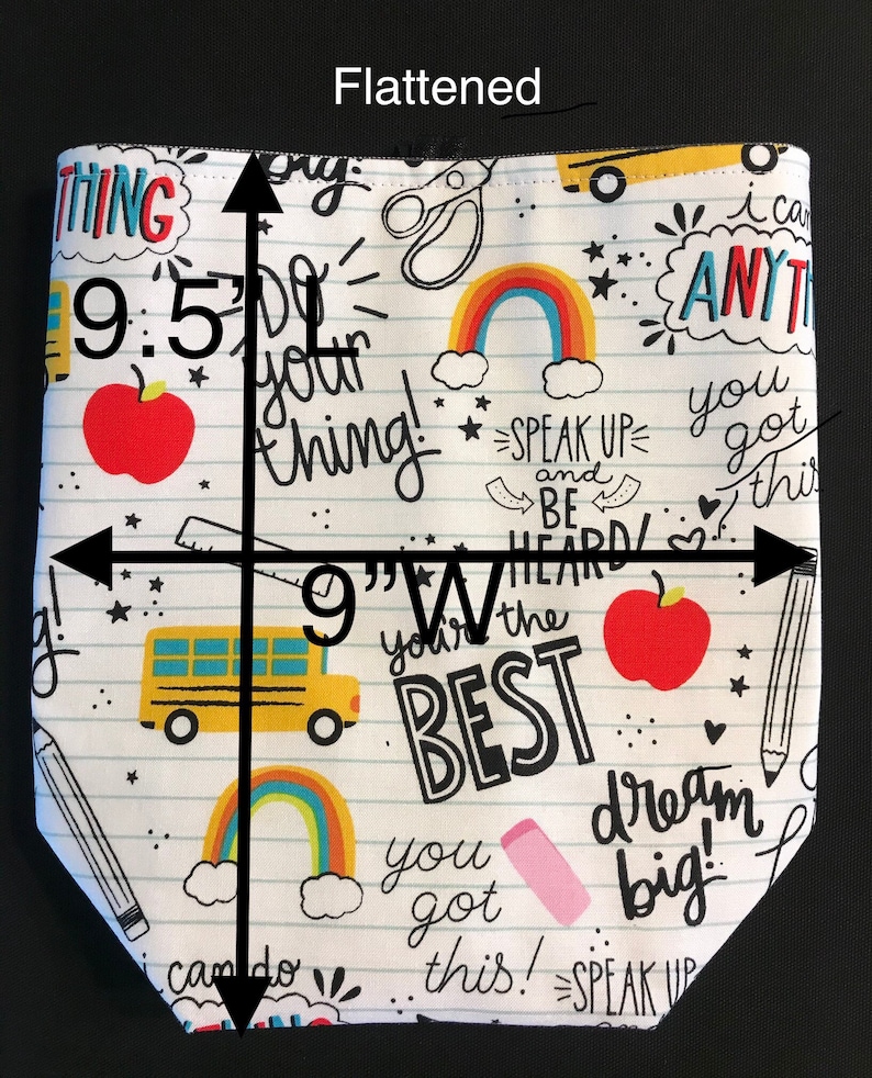 K&ouml;nnte beinhalten: Eine wei&szlig;e Stofftasche mit einem Schul-Motiv. Die Tasche zeigt einen gelben Schulbus, rote &Auml;pfel, Regenb&ouml;gen und inspirierende Spr&uuml;che wie "You got this!" und "Dream big!" Die Tasche ist 24,1 cm hoch und 22,9 cm breit.