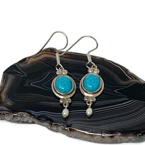 May include: A pair of silver earrings with turquoise stones and pearl accents.