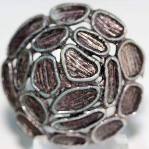 May include: A silver-toned metal ring with a textured, organic design. The ring is made up of many small, interconnected circles that create a three-dimensional effect.