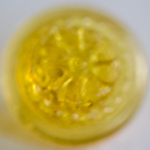 May include: A close-up of a yellow, translucent, round object with a starburst pattern. The object is slightly blurred.