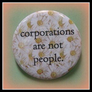 May include: A white button with a daisy pattern and the text "corporations are not people."