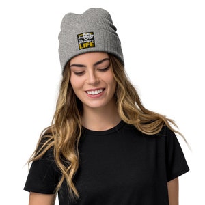 May include: A grey beanie with a black square patch that says "the theatre LIFE" in yellow letters. The patch has a white theatrical mask graphic.