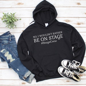 May include: Black hooded sweatshirt with the text "NO, I WOULDN'T RATHER BE ON STAGE #StageCrew" in white.