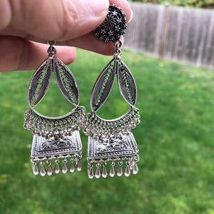 Puede incluir: Pendientes de plata con forma de l&aacute;grima y dise&ntilde;o cuadrado. Los pendientes tienen un dise&ntilde;o floral plateado y una borla plateada.