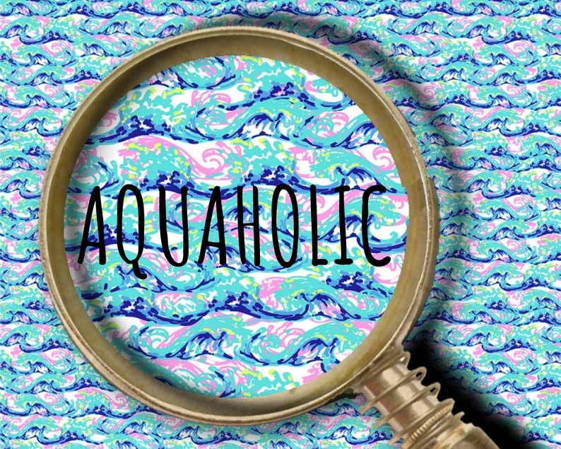 May include: A magnifying glass with a metallic frame is positioned over a repeating pattern of stylized ocean waves in shades of turquoise, light blue, dark blue, and pink. The word AQUAHOLIC is printed in black capital letters across the center.