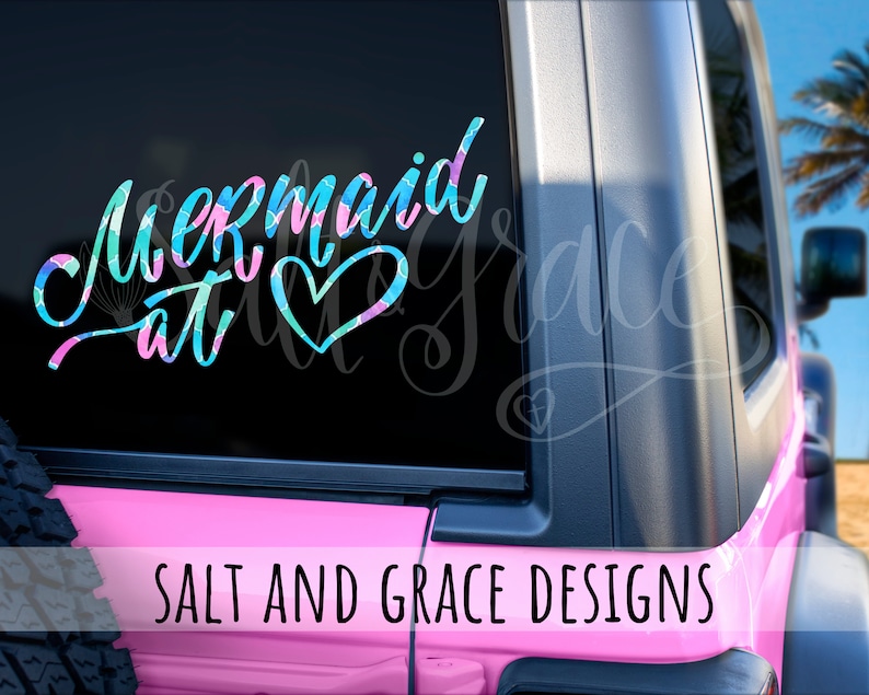 May include: A pink Jeep with a mermaid at heart decal on the rear window. The decal is in blue, green, and pink colours. The text "Salt and Grace Designs" is printed on the back of the Jeep.