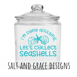 May include: A clear glass jar with a blue and white design that says "I'm done adulting. Let's collect seashells." The jar is sitting on a white background.