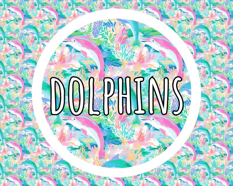 May include: A repeating pattern featuring pink dolphins swimming among colorful coral reefs and aquatic plants. Centered in the image is a large white circle containing the word DOLPHINS in bold, black, outlined capital letters.