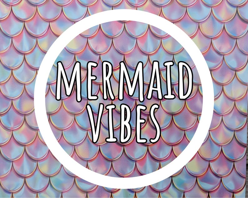 May include: A repeating pattern of iridescent, holographic fish scales in shades of pink, blue, and purple. Centered in the image is a white circular frame containing the black text MERMAID VIBES in a bold, sans-serif, outlined font.