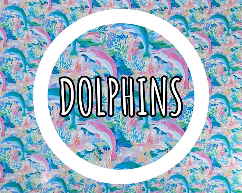 Op de afbeelding: Een kleurrijk patroon met dolfijnen in blauw en roze, omringd door koraal en waterplanten. Het woord "DOLPHINS" staat in een witte cirkel. Geschikt voor diverse toepassingen.