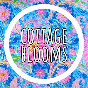 K&ouml;nnte beinhalten: Ein lebhaftes Blumenmuster in Blau-, Rosa- und Gelbt&ouml;nen mit dem Text "COTTAGE BLOOMS" in einem wei&szlig;en Kreis. Das Design zeigt stilisierte Blumen und paisleyartige Elemente, die eine fr&ouml;hliche und farbenfrohe &Auml;sthetik schaffen.