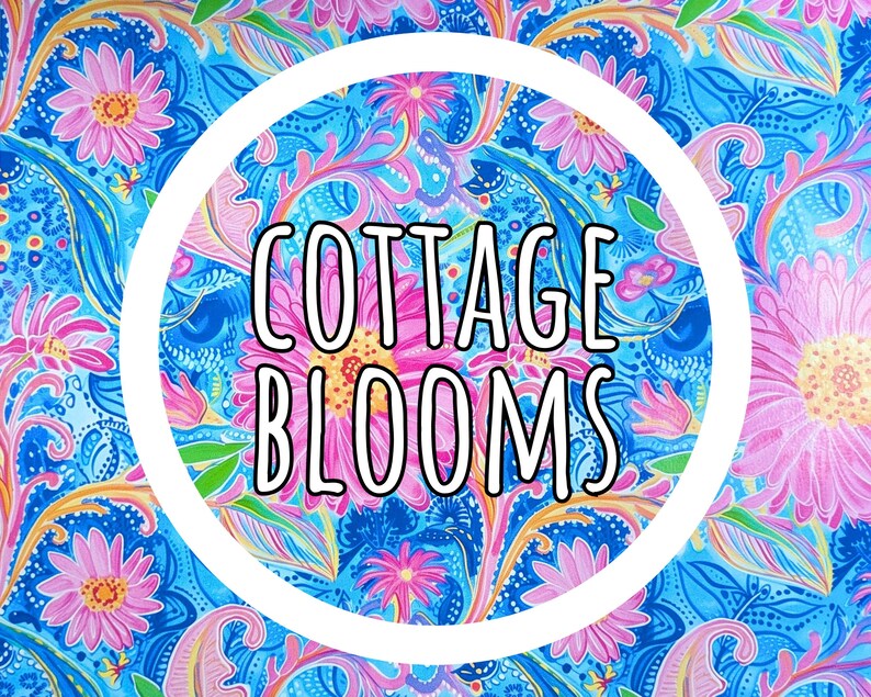 K&ouml;nnte beinhalten: Ein lebhaftes Blumenmuster in Blau-, Rosa- und Gelbt&ouml;nen mit dem Text "COTTAGE BLOOMS" in einem wei&szlig;en Kreis. Das Design zeigt stilisierte Blumen und paisleyartige Elemente, die eine fr&ouml;hliche und farbenfrohe &Auml;sthetik schaffen.