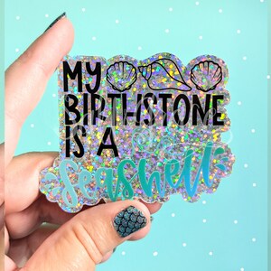 May include: A holographic sticker with glitter and seashells that says "My Birthstone is a Seashell".