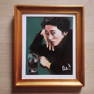 Puede incluir: Retrato de pintura al óleo en un marco dorado. El cuadro representa a una persona con cabello oscuro, apoyando la cabeza en su mano. Un vaso de líquido está sobre la mesa. El fondo es verde oscuro.