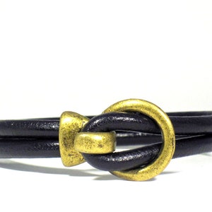 Men's bracelet made of 5 mm. black leather cord and bronze color closure.