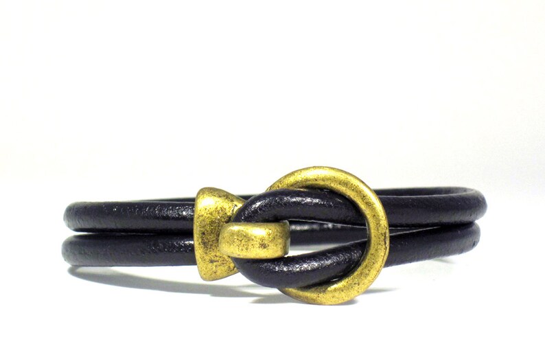 Men's bracelet made of 5 mm. black leather cord and bronze color closure.