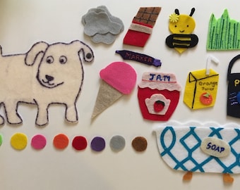 May include: A felt craft set with various shapes and colors, including a dog, a bee, a bathtub, a paint can, a jar of jam, a juice box, an ice cream cone, a marker, a cloud, and a patch of grass. There are also 10 small felt circles in various colors.