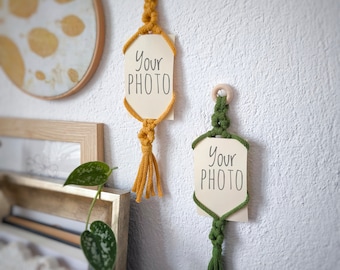 May include: Two macrame wall hangings with wooden rings and tassels. The hangings have a white card with the text "Your Photo" on them. One hanging is yellow and the other is green.