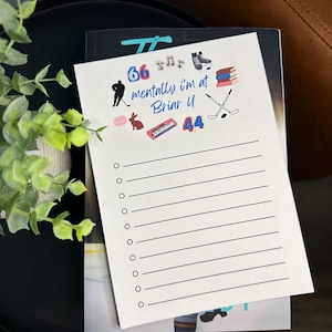 May include: A white notepad with a list of lines and colorful illustrations. The notepad has the text "66 mentally I'm at Briar U 44". The illustrations include a hockey player, musical notes, a bunny, a piano, and hockey sticks.