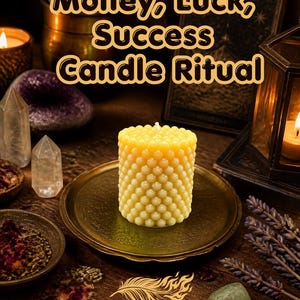 May include: A yellow cylindrical candle with a textured honeycomb surface sits on a round brass plate. The text "Money, Luck, Success Candle Ritual" appears at the top, and "PHOENIX SOUL" with a feather icon is printed at the bottom of the image.