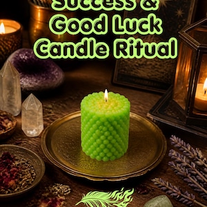 May include: A bright green, textured, cylindrical pillar candle with a lit wick sits on a round brass plate. The text "Success & Good Luck Candle Ritual" appears above, and "PHOENIX SOUL" with a feather icon is printed at the bottom of the image.