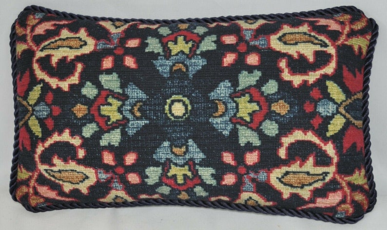 Puede incluir: Una almohada decorativa con fondo negro y un estampado floral colorido. La almohada tiene un dise&ntilde;o floral de color azul oscuro, rojo, verde y amarillo. La almohada tiene un ribete azul oscuro.